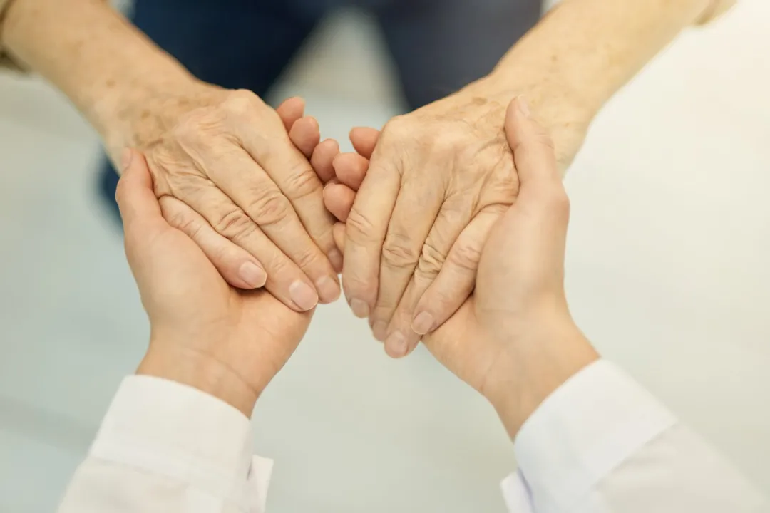 Caring hands supporting elderly patient - representing Edencare's compassionate geriatric care approach